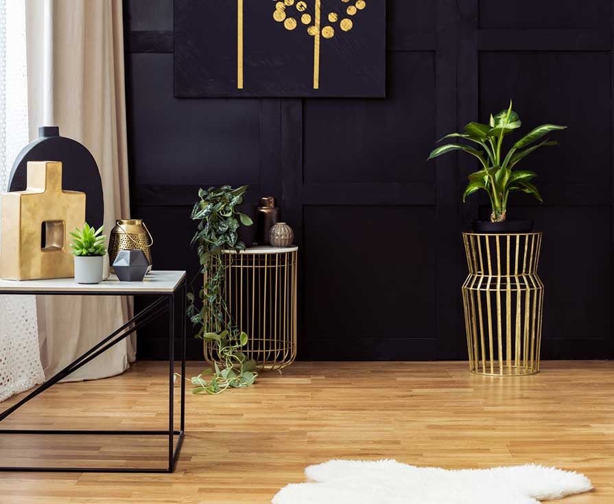 Elegant living room interior with golden accents, painting on a black wall, plants and fur rug. Real photo